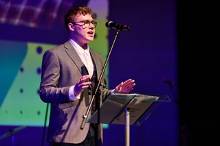 Sam Webster on stage speaking